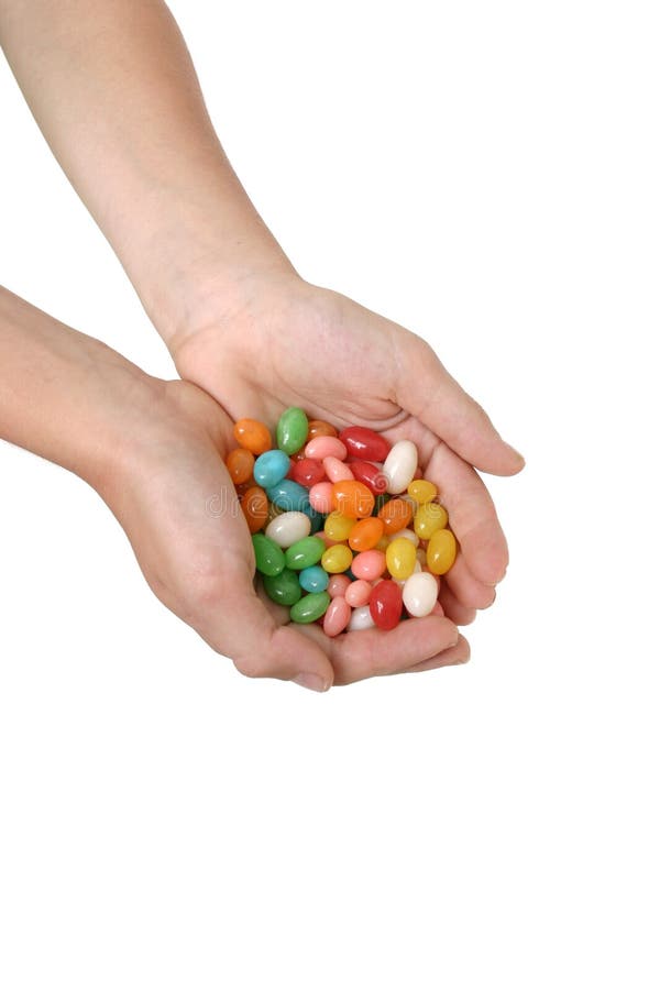 A child holds a handful of coloured lollies / candy. A child holds a handful of coloured lollies / candy.