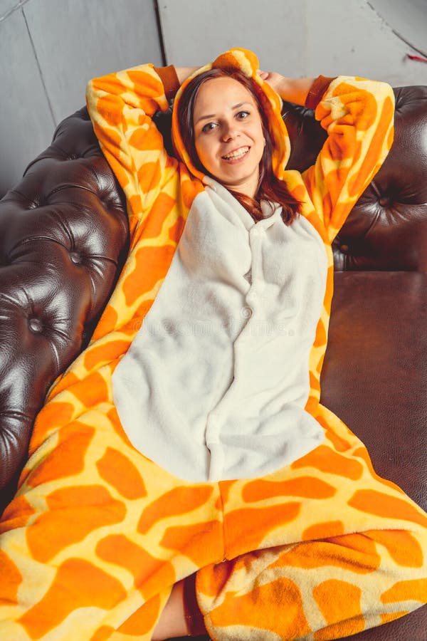 Pyjamas für Halloween in Form einer Giraffe Emotionales Porträt eines Mädchens auf einem Sofahintergrund Verrückter und lustiger stockfoto Pyjamas für Halloween in Form einer Giraffe Emotionales Porträt eines Mädchens auf einem Sofahintergrund Verrückter und lustiger stockfoto