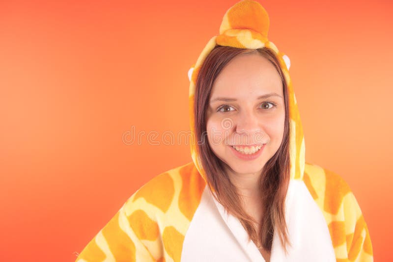 Pyjamas i form av en giraff emotionell stående av en flicka på en orange bakgrund galen och rolig kvinna i en dräkt _ royaltyfri foto Pyjamas i form av en giraff emotionell stående av en flicka på en orange bakgrund galen och rolig kvinna i en dräkt _ royaltyfri foto