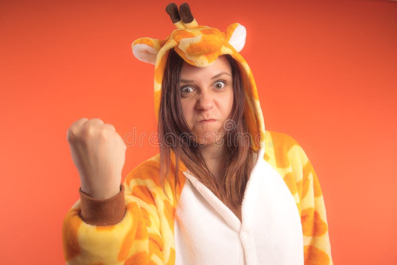 Pyjamas i form av en giraff emotionell stående av en flicka på en orange bakgrund galen och rolig kvinna i en dräkt _ arkivbilder Pyjamas i form av en giraff emotionell stående av en flicka på en orange bakgrund galen och rolig kvinna i en dräkt _ arkivbilder