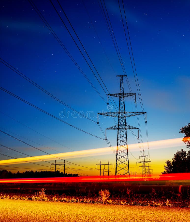 Pylônes et lignes à haute tension de l'électricité la nuit avec des feux de signalisation dans l'avant photos stock Pylônes et lignes à haute tension de l'électricité la nuit avec des feux de signalisation dans l'avant photos stock
