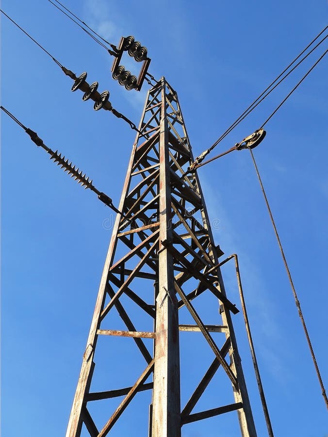 Pylon with wires under high voltage over the railway against the blue sky on a day royalty free stock images