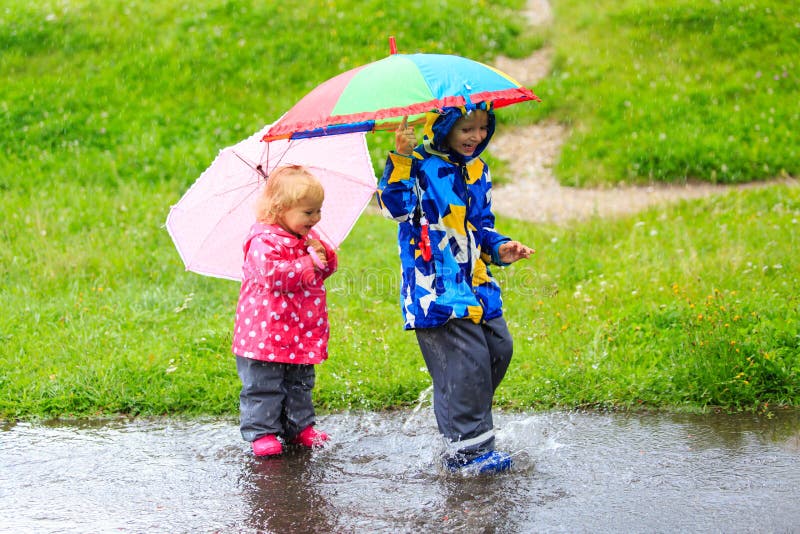 Pys och flicka som har gyckel på regn arkivfoton Pys och flicka som har gyckel på regn arkivfoton