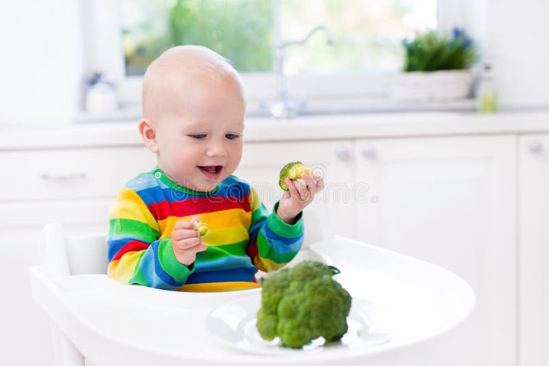 Pys som äter broccoli i vitt kök fotografering för bildbyråer Pys som äter broccoli i vitt kök fotografering för bildbyråer
