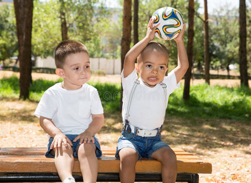 Pyser: Afrikanska amerikanen och caucasianen med fotbollbollen parkerar in på naturen på sommar arkivfoto Pyser: Afrikanska amerikanen och caucasianen med fotbollbollen parkerar in på naturen på sommar arkivfoto