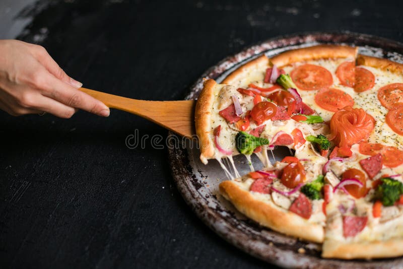 Pyszny kawałek sera, wyciągnięty z pełnej pizzy najwyższej pieczonej świeżo z pieca obok składników fotografia stock
