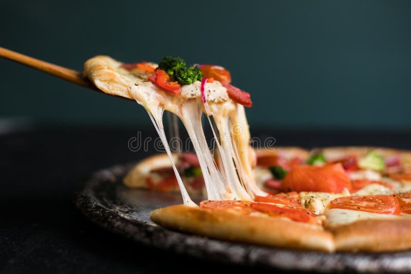 Pyszny kawałek sera, wyciągnięty z pełnej pizzy najwyższej pieczonej świeżo z pieca obok składników zdjęcia stock