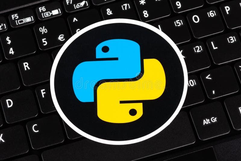 Python programming language round logo sticker, symbol label laying on a laptop keyboard, closeup, top view. Simple programming royalty free stock photography