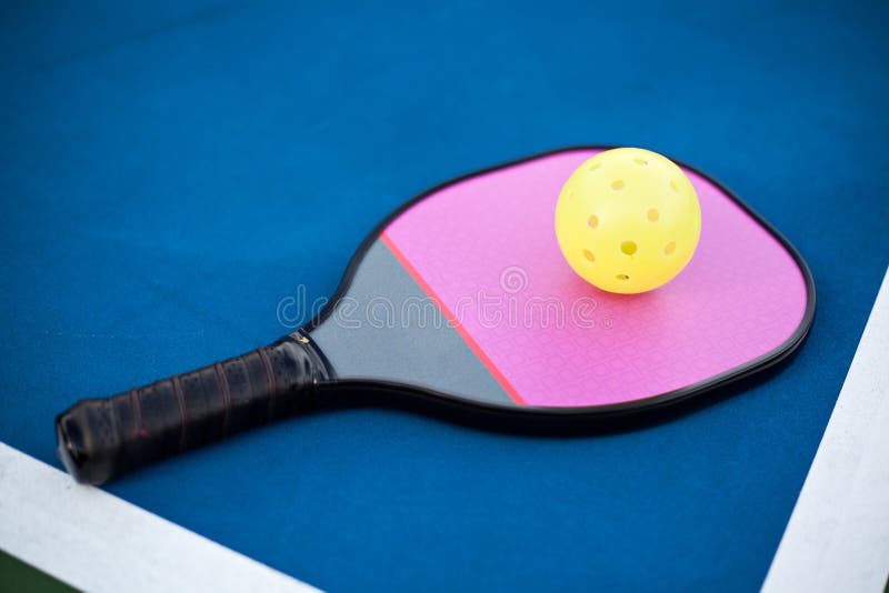 Pickleball paddle and ball on an outdoor court. Pickleball paddle and ball on an outdoor court