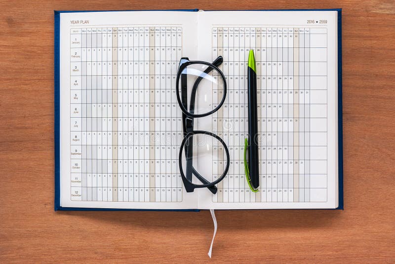 Página aberta do calendário do livro do planejador do diário com vidros e pena fotografia de stock Página aberta do calendário do livro do planejador do diário com vidros e pena fotografia de stock