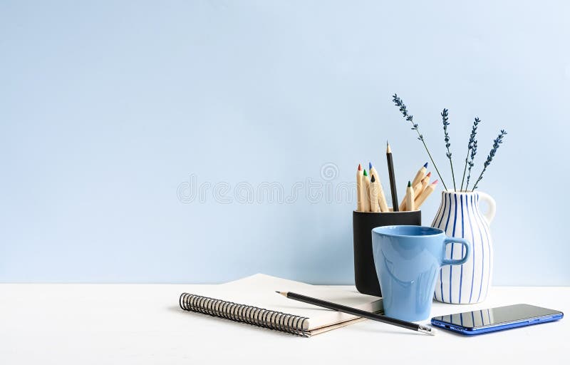 Página de inicio y oficina con cartón, teléfono, lápices, café sobre una mesa blanca sobre una pared azul claro