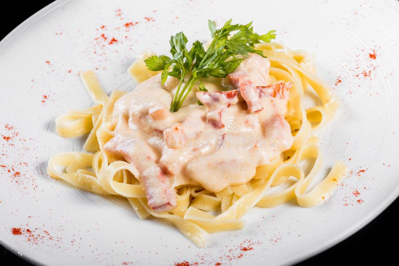 Pâtes de Fettuccine avec de la viande, la sauce crème et des herbes, dans la cuvette d'isolement sur le fond noir images stock Pâtes de Fettuccine avec de la viande, la sauce crème et des herbes, dans la cuvette d'isolement sur le fond noir images stock