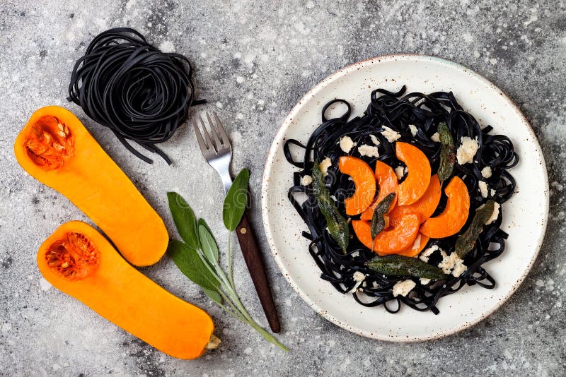 Pâtes noires avec la courge de butternut rôtie, le parmesan et la sauge frite Concept noir et orange de Halloween de partie de dî photo stock Pâtes noires avec la courge de butternut rôtie, le parmesan et la sauge frite Concept noir et orange de Halloween de partie de dî photo stock