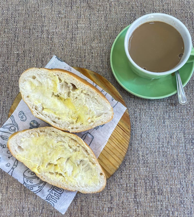 Pão com manteiga em bandeja de madeira e café com leite fotografia de stock