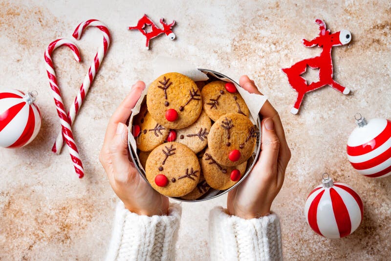 Pão de Natal Mãos da mulher segurando caixa de biscoitos de renas ruidosas vermelhas Doces decorados em casa festivos imagem de stock