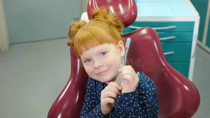 Pädiatrische Zahnheilkundekonzept. mit Glamour Mädchen in zahnmedizinischem Stuhl. schönes redhaired Mädchen, das Spaß in zahnmedi