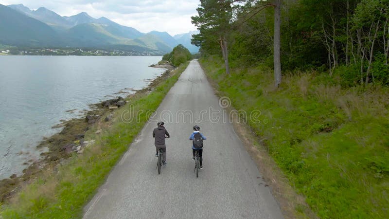 Pärchen, die Fahrräder an einem Fjord fahren, in der Nordantenne