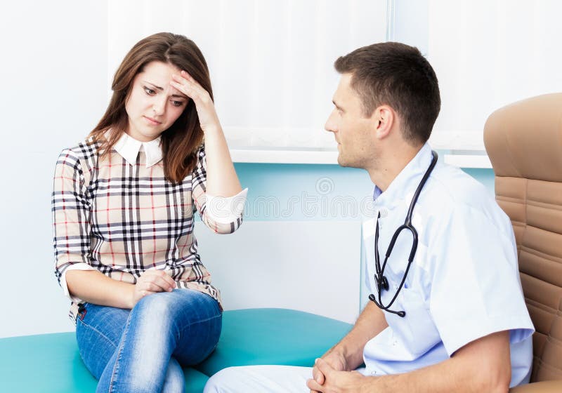 På ett mottagande på det tålmodiga innehavet för doktor Female hans huvud Besöka en doktor i den sjuka kvinnan för sjukhuset migr fotografering för bildbyråer På ett mottagande på det tålmodiga innehavet för doktor Female hans huvud Besöka en doktor i den sjuka kvinnan för sjukhuset migr fotografering för bildbyråer