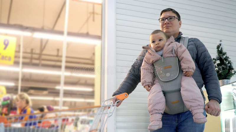 Père avec son enfant dans le transporteur de bébé dans le centre commercial, concept de parenting d'attachement