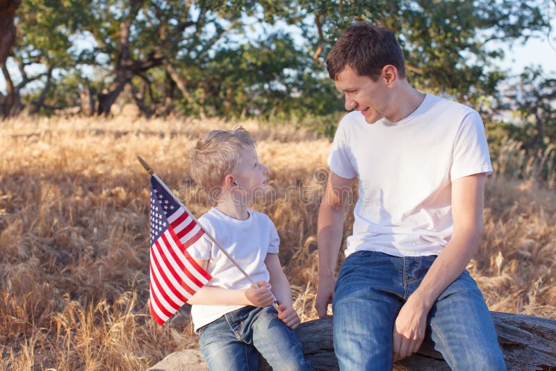 Père beau et son petit fils tenant le celebra de drapeau américain photographie stock libre de droits Père beau et son petit fils tenant le celebra de drapeau américain photographie stock libre de droits