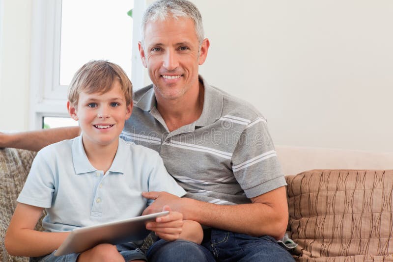 Père de sourire et son fils à l'aide d'un ordinateur de tablette dans un salon