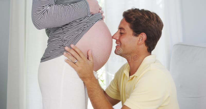 Père enthousiaste embrassant le ventre de l'épouse enceinte image libre de droits Père enthousiaste embrassant le ventre de l'épouse enceinte image libre de droits