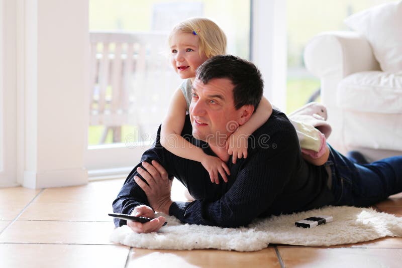 Père et fille regardant la TV à la maison photographie stock libre de droits Père et fille regardant la TV à la maison photographie stock libre de droits