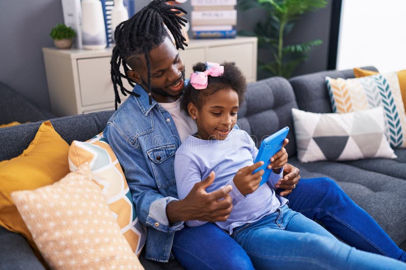 Père et fille regarder la vidéo sur le pavé tactile assis sur le canapé à la maison photo libre de droits