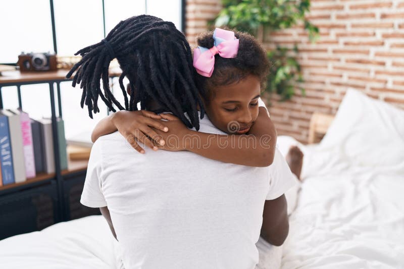 Père et fille s'embrassant assis sur le lit dans la chambre photo libre de droits