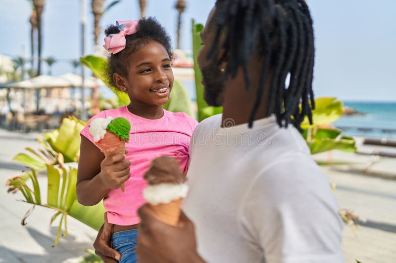 Père et fille se prenant dans les bras en train de manger de la crème glacée en bord de mer image stock