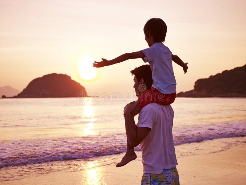 Young asian father carrying son on shoulder on beach at sunrise. Young asian father carrying son on shoulder on beach at sunrise.