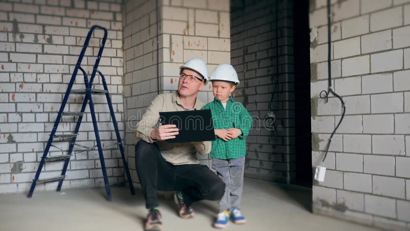 Père et fils en casques blancs sur un chantier de construction
