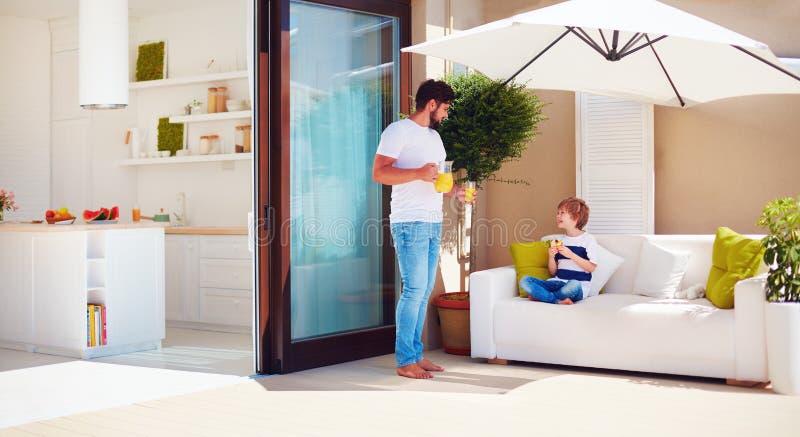 Père et fils, famille détendant sur le patio de dessus de toit avec la cuisine de l'espace ouvert au jour d'été chaud images libres de droits Père et fils, famille détendant sur le patio de dessus de toit avec la cuisine de l'espace ouvert au jour d'été chaud images libres de droits