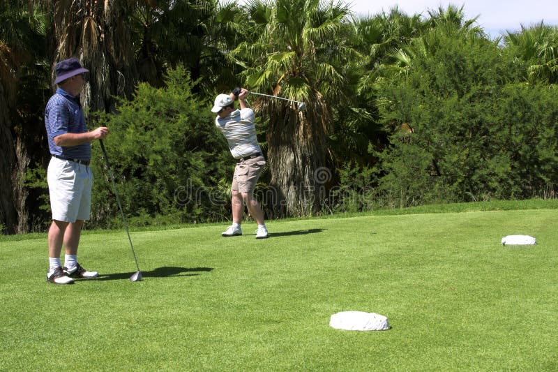 Père et fils jouant au golf.