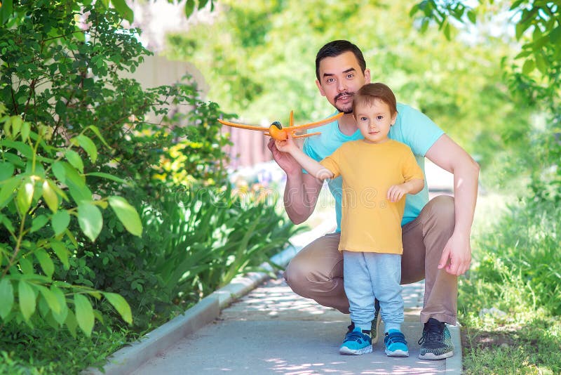 Père et fils jouant ensemble dehors dans le jour d'été : le papa et l'enfant lancent l'avion de jouet Nouveau début, concept pare image stock Père et fils jouant ensemble dehors dans le jour d'été : le papa et l'enfant lancent l'avion de jouet Nouveau début, concept pare image stock