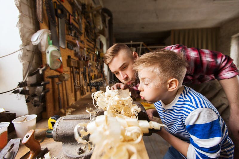 Père et petit fils avec la planche en bois à l'atelier photo stock Père et petit fils avec la planche en bois à l'atelier photo stock