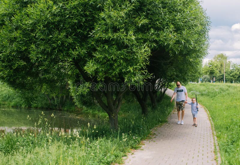 Père et peu de fils marchant ensemble en parc d'été images libres de droits Père et peu de fils marchant ensemble en parc d'été images libres de droits