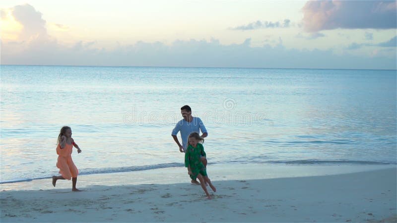 Père heureux avec le jeu d'enfants sur la plage Famille heureuse ayant l'amusement pendant des vacances de plage d'été banque de vidéos