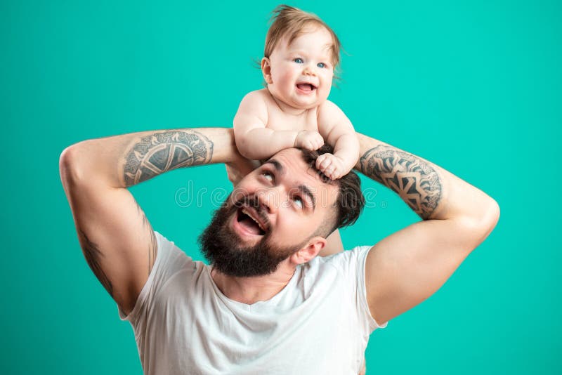 Père heureux portant son nourrisson fille sur le cou d'isolement au-dessus du fond bleu