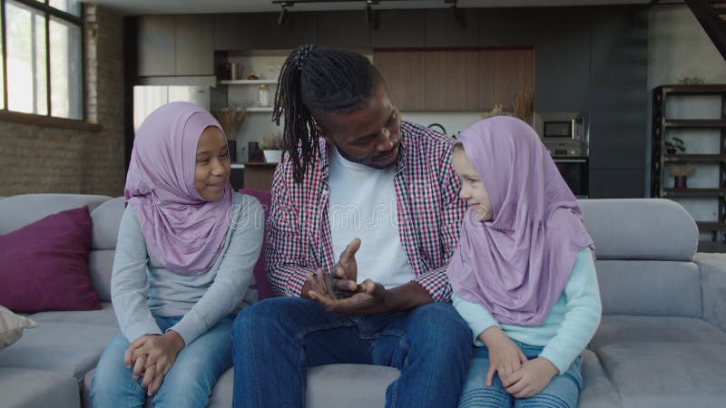 Père noir positif et jolies petites filles musulmanes multiraciales se lient et parlent à la maison banque de vidéos