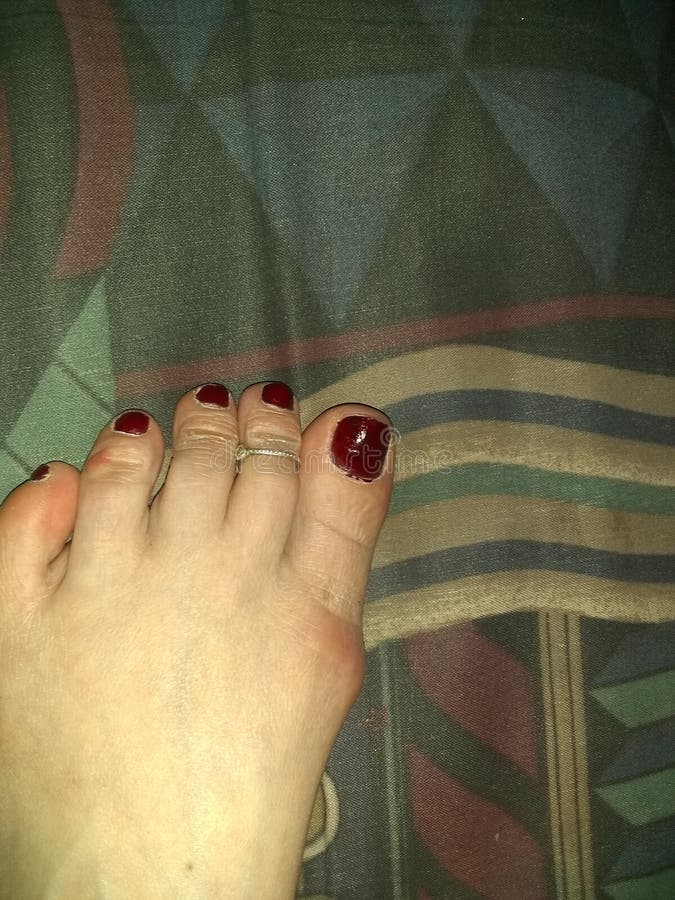 Pé fêmea caucasiano com verniz para as unhas vermelho marrom e anel de prata esterlino do dedo do pé, formas geométricas no fundo imagens de stock Pé fêmea caucasiano com verniz para as unhas vermelho marrom e anel de prata esterlino do dedo do pé, formas geométricas no fundo imagens de stock
