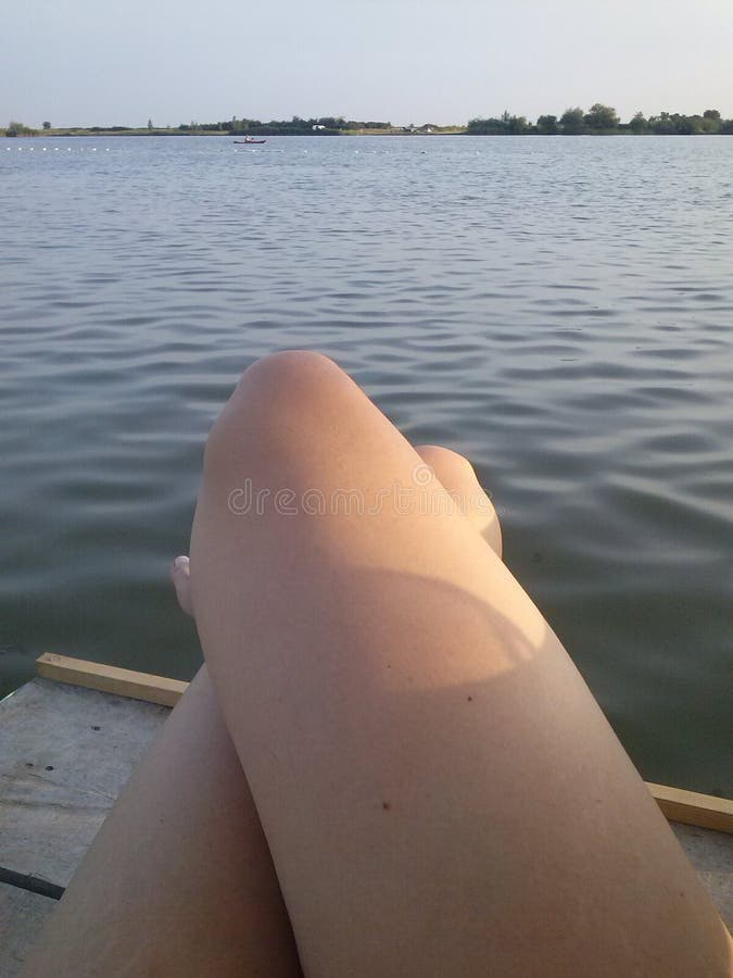 Pés cruzados das mulheres viradas à água imagens de stock Pés cruzados das mulheres viradas à água imagens de stock