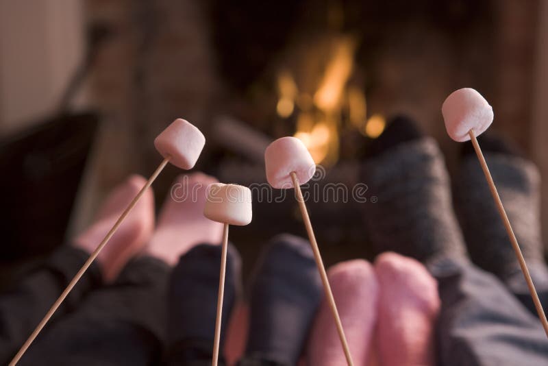 Pés que aquecem-se em uma chaminé com marshmallows imagem de stock Pés que aquecem-se em uma chaminé com marshmallows imagem de stock