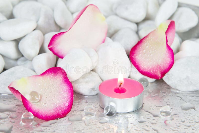 Pétalos de Rose y una vela encendida para una decoración del balneario imagenes de archivo Pétalos de Rose y una vela encendida para una decoración del balneario imagenes de archivo