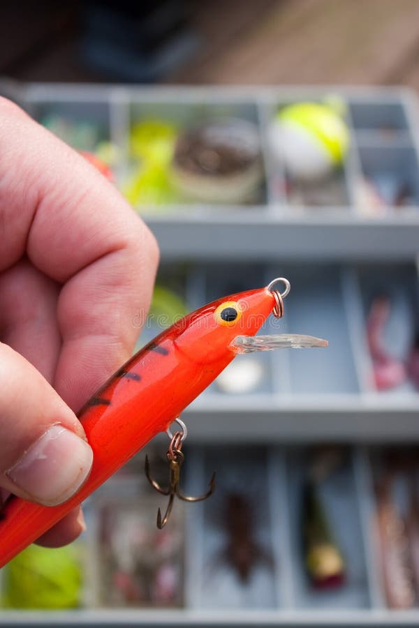 A fishermen selects the lure from his tackle box that he is going to go fishing with. A fishermen selects the lure from his tackle box that he is going to go fishing with.