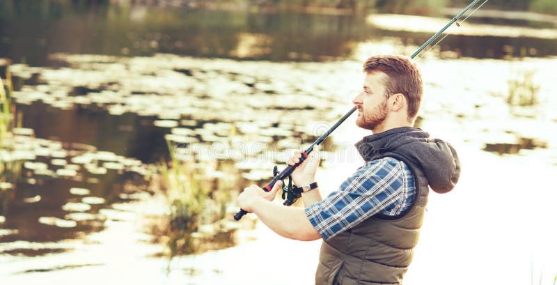 Pêcheur avec un poisson de capture de rotation et d'amorce sur un lac ou une rivière Homme un week-end avec une route de pêche Pa photo libre de droits Pêcheur avec un poisson de capture de rotation et d'amorce sur un lac ou une rivière Homme un week-end avec une route de pêche Pa photo libre de droits