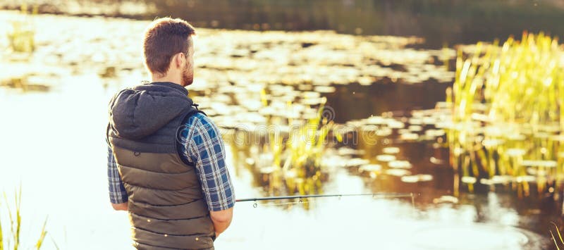 Pêcheur avec un poisson de capture de rotation et d'amorce sur un lac ou une rivière Homme un week-end avec une route de pêche Pa images libres de droits Pêcheur avec un poisson de capture de rotation et d'amorce sur un lac ou une rivière Homme un week-end avec une route de pêche Pa images libres de droits