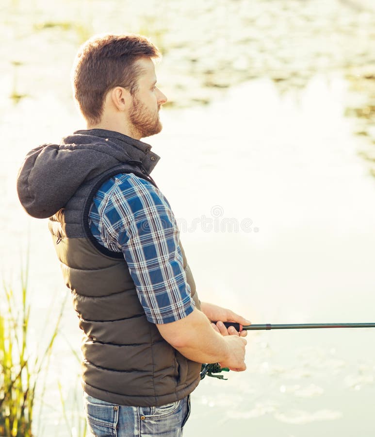 Pêcheur avec un poisson de capture de rotation et d'amorce sur un lac ou une rivière Homme un week-end avec une route de pêche Pa images stock Pêcheur avec un poisson de capture de rotation et d'amorce sur un lac ou une rivière Homme un week-end avec une route de pêche Pa images stock