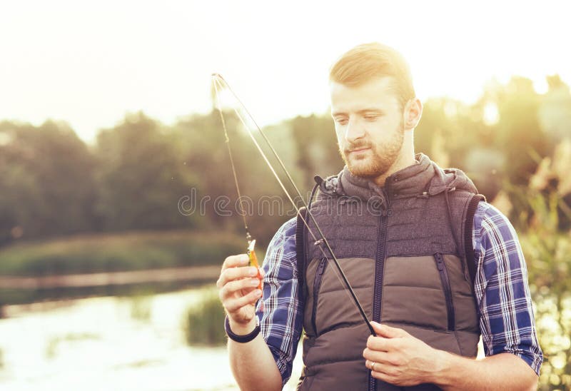 Pêcheur avec un poisson de capture de rotation et d'amorce sur un lac ou une rivière Homme un week-end avec une route de pêche Pa photos libres de droits Pêcheur avec un poisson de capture de rotation et d'amorce sur un lac ou une rivière Homme un week-end avec une route de pêche Pa photos libres de droits