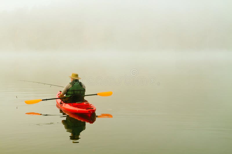 Pêcheur dans le kayak rouge photos stock Pêcheur dans le kayak rouge photos stock